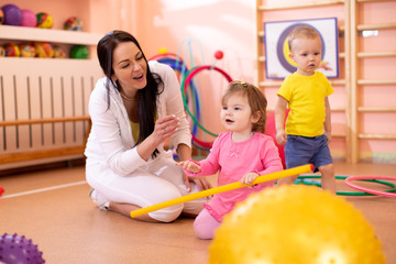 Fototapeta premium Group of babies in gym with nursery teacher