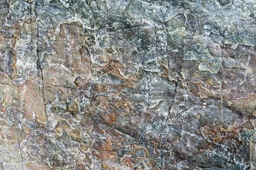 Macro view of cracked stone surface gray and brown color. Detailed nature pattern texture or background taken in natural environment. Weathered over years, unique, inimitable effect to textured design