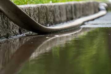 Reflektion eines Schlauches in Wasserlacke