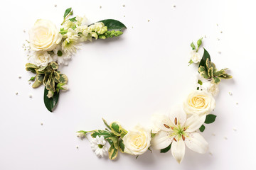 White roses, lily, gerbera over light background. Flat lay, top view. Creative layout. Spring or summer banner with copy space. Flowers composition.