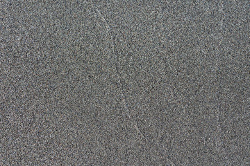 Close-up macro view of black color volcanic sand surface. Detailed nature background or pattern texture taken in natural environment. Weathered many years, inimitable, unique effect to textured design