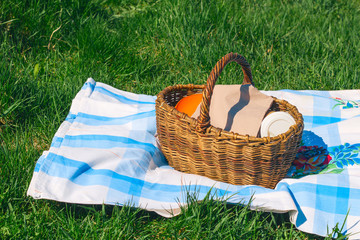 wicker basket on the tablecloth on a background of green grass ,picnic concept