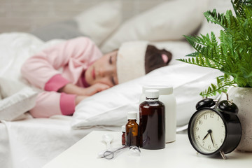 Obraz na płótnie Canvas Sick little child girl lying in bed with thermometer. Cold flu season. focus on medication