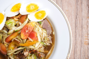 Spicy cucumber salad served with boil egg. Traditional food of asian. Spicy food. In white plate over wooden table.