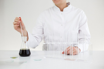 Scientist with gloves checking a pharmaceutical cbd oil in a laboratory on watch glass