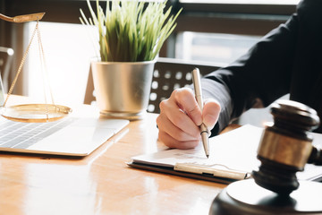 Business woman and lawyers discussing contract papers with brass scale on wooden desk in office....