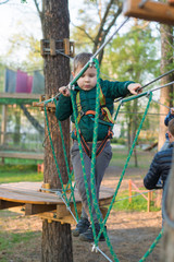 Little boy in a rope park. Active physical recreation of the child in the fresh air in the park. Training for children.