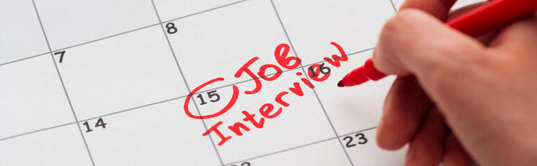panoramic shot of man writing with red marker on calendar with job interview lettering