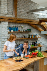 Lovely cheerful couple cooking dinner together and having fun at rustic kitchen