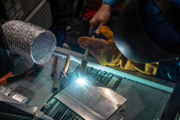 The construction worker welding the metal part. The welding operator working with safety mask.