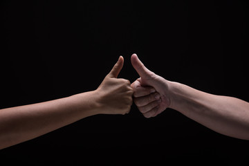 Two hand hit together and show thumb up and touch on black background.