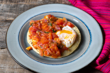 Mexican food: Fried egg rancheros with sauce and corn tortilla