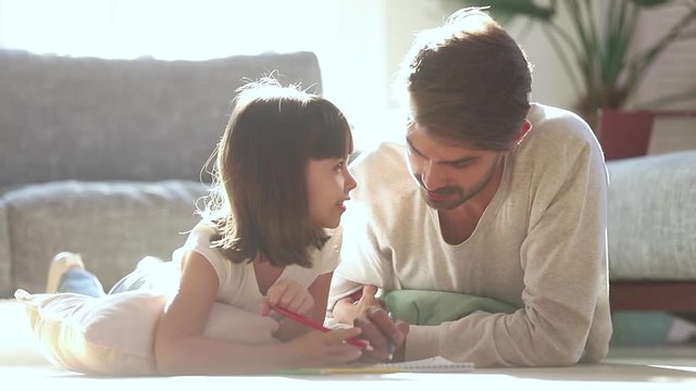 Dad and kid daughter draw with pencils on warm floor