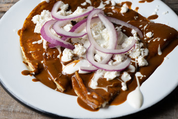 Mexican food: Mole sauce enchiladas with cream and fresh cheese