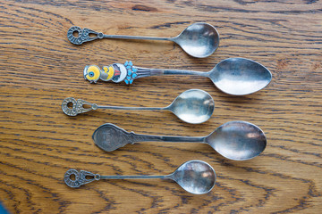 Five antique, decorative spoons on an oak table