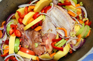 The wing of turkey with colourful vegetables. Raw meat before cooking. Poultry dishes. Potatoes, pepper, zucchini and onion in the old pan. Thanksgiving day healthy food concept.