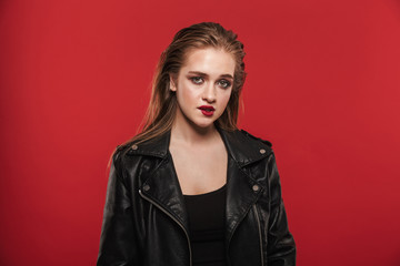 Beautiful young amazing woman with bright makeup red lipstick posing isolated over red wall background.