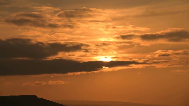 Superzoom plan timelapse sunset through sunset clouds in orange tones. Low key