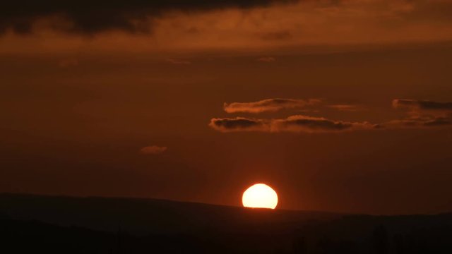 Superzoom plan timelapse sunset through sunset clouds in orange tones. Low key