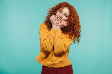 Photo of joyous girl 20s with curly ginger hair smiling and looking at camera