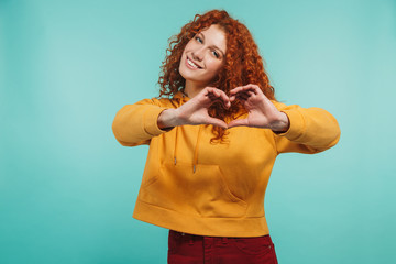 Portrait of cheery redhead woman 20s wearing leather jacket smiling and showing heart shape with fingers