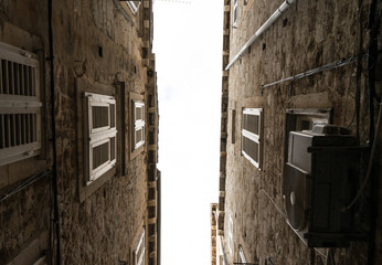 Fototapeta na wymiar The narrow streets of the old city of Dubrovnik in Croatia, the bottom view of the sky between the stone walls of houses