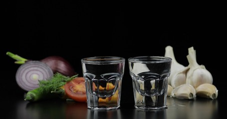 Alcohol drink vodka in shot glasses. Background with vegetables