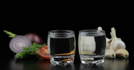 Alcohol drink vodka in shot glasses. Background with vegetables
