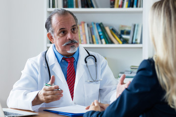 Älterer Chefarzt spricht mit Patientin