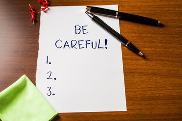 Text sign showing Be Careful. Business photo showcasing making sure of avoiding potential danger mishap or harm Blank stationary paper wooden table fountain pen cloth rag pins to fix