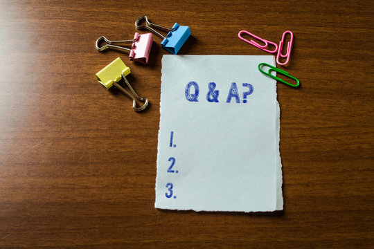 Handwriting text writing Q And A Question. Conceptual photo in which demonstrating asks questions and another one answers them Blank stationary paper set three colored clips binders lying wooden table