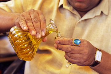 Man pouring essential oil from glass bottle close up