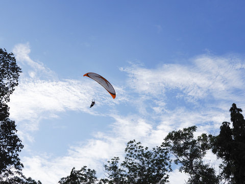 A man flying in the beautiful blue cloudy sky, parachute with a motor, paramotor. Sky driving. Extreme sport, adventure, freedom concept.
