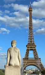 Statue of woman looks the big Eiffel Tower in Paris
