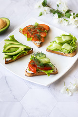 Vegetarian sandwiches with avocado, tomatoes and cucumbers on a light background