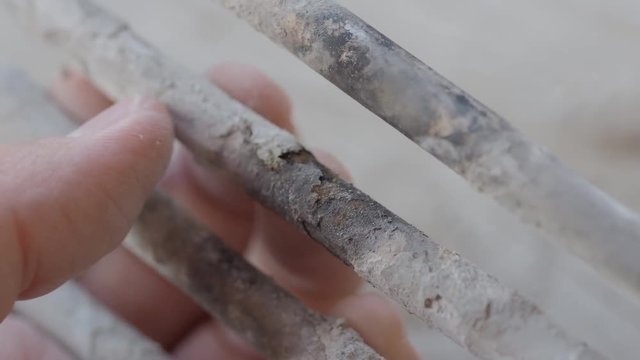 Burnt-out heating element from a washing machine. Man is touching turbular electric heating element covered with limescale.