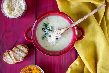 Cheese cream soup on a red wooden background. White bread croutons. Ingredients.