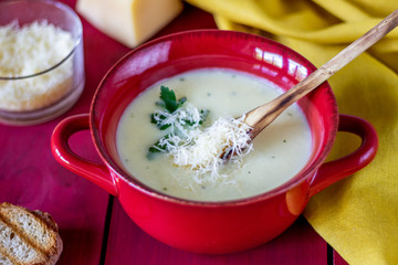 Cheese cream soup on a red wooden background. White bread croutons. Ingredients.