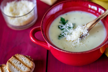Cheese cream soup on a red wooden background. White bread croutons. Ingredients.