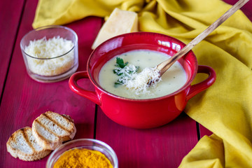 Cheese cream soup on a red wooden background. White bread croutons. Ingredients.