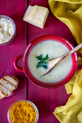 Cheese cream soup on a red wooden background. White bread croutons. Ingredients.