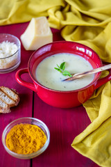 Cheese cream soup on a red wooden background. White bread croutons. Ingredients.