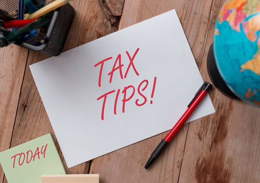 Word writing text Tax Tips. Business photo showcasing compulsory contribution to state revenue levied by government Writing equipments and sheets with artificial globe on the wooden desk