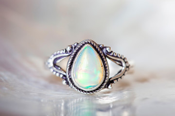 Silver ring with opal mineral gemstone on pearl background