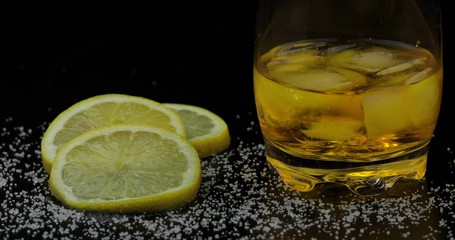 Whiskey with ice cubes in drinking glass. Black background. Glass of rum alcohol