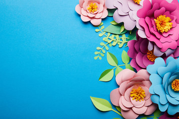 top view of colorful paper cut flowers with green leaves on blue background with copy space - obrazy, fototapety, plakaty