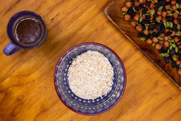 Oatmeal cereals with nuts and coffee cup. Healthy breakfast table top view photo. Grain or musli for breakfast flat lay