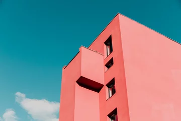 Vlies Fototapete Koralle Blick von unten auf ein rosafarbenes, modernes Haus und einen Himmel. Vintage Pastellfarben, minimalistisches Konzept.