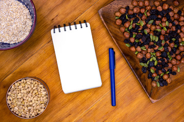Oatmeal and blank page notepad on wooden table. Healthy breakfast recipe. Porridge musli and notebook top view photo