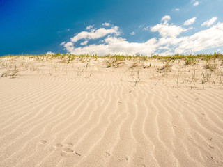 Sand pattern, blue cloudy sky. Warm summer day.